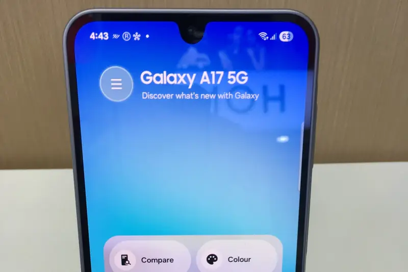 Top half of a Samsung Galaxy A17 5G on a store display, its screen reading "Galaxy A17 5G, Discover what's new with Galaxy"