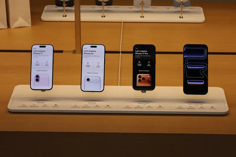 iPhone 17, iPhone Air, iPhone 17 Pro and iPhone 17 Pro Max on a wooden display stand at an Apple Store, each screen naming its model