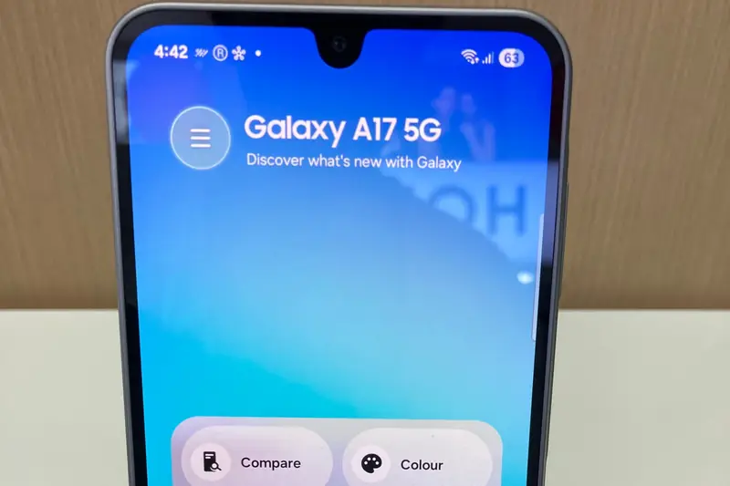 Top half of a Samsung Galaxy A17 5G on a store display, its screen reading "Galaxy A17 5G" above Compare and Colour buttons