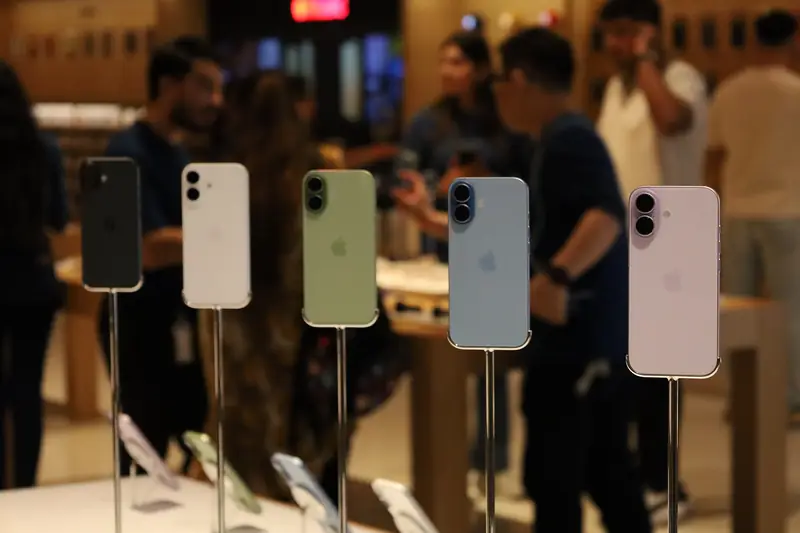 Five iPhone 17 phones on display stands with their backs to the camera, in black, white, sage, mist blue and lavender, in an Apple Store
