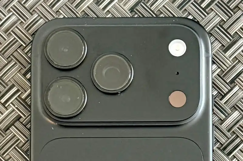 Close-up of the back of a black iPhone 18 Pro lying on a woven placemat, showing its camera plateau with three lenses