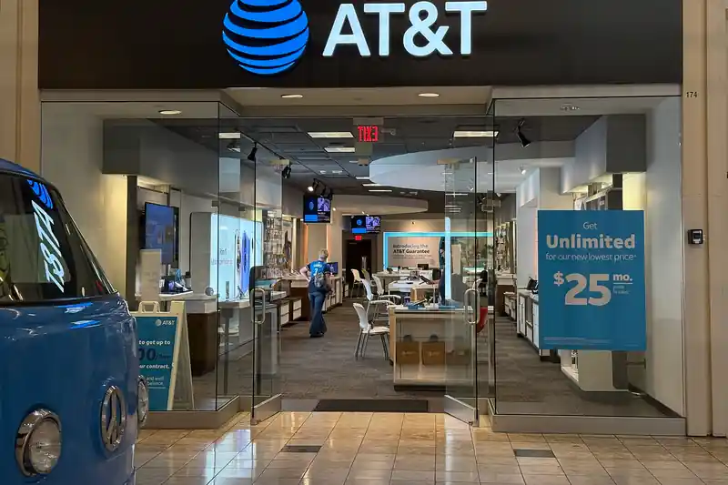 Entrance of an AT&T store in a shopping mall, with phone displays inside and a poster advertising unlimited plans